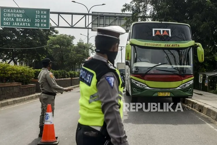 Polisi menghentikan bus saat penerapan pelarangan mudik di Jalur Pantura, Perbatasan Kabupaten Bekasi dengan Karawang, Kabupaten Bekasi, Jawa Barat, Sabtu (25/4/2020). Hari kedua penerapan pelarangan mudik di jalur pantura masih banyak pengendara yang memaksakan untuk mudik dan tidak menerapkan jarak sosial. Foto: Republika/Putra M. Akbar