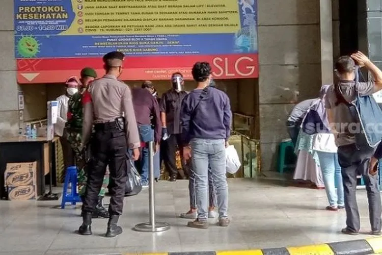 Petugas gabungan dari TNI dan Polri saat memeriksa suhu tubuh pengunjung di Pasar Tanah Abang. (Suara.com/Arga).