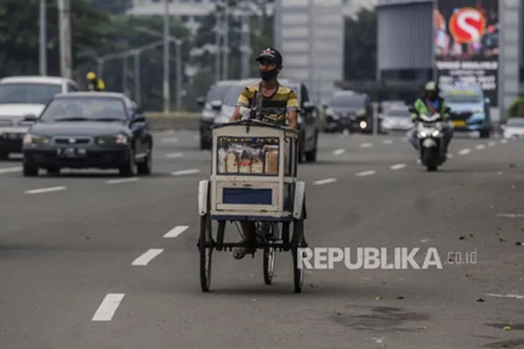 Pedagang menggunakan masker saat melintasi kawasan Sudirman, Jakarta,Ahad (11/10). Pemerintah Provinsi DKI Jakarta mengurangi kebijakan rem darurat di Ibu Kota dengan kembali memberlakukan Pembatasan Sosial Berskala Besar (PSBB) Transisi mulai Senin (12/10) hingga Senin (25/10). Republika/Putra M. Akbar
