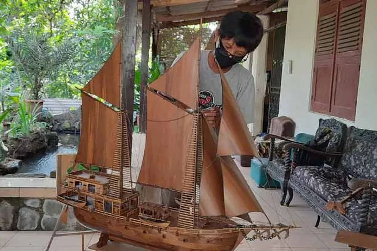 Arifin sedang merancang miniatur perahu pinisi.