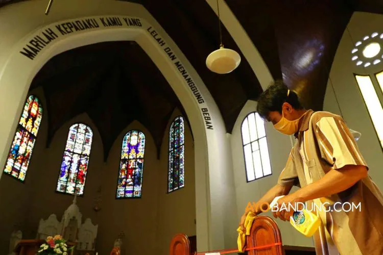 Seorang petugas membersihkan kursi menggunakan cairan desinfektan di Gereja Katedral Santo Petrus, Jalan Merdeka, Kota Bandung, Jumat (12/6/2020). (Ayobandung.com/Irfan Al-Faritsi)