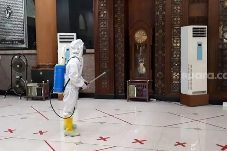 Petugas berpakaian APD lengkap saat menyemprot disinfektan di Masjid Agung Al Barkah Kota Bekasi. (Suaracom/Bagaskara).