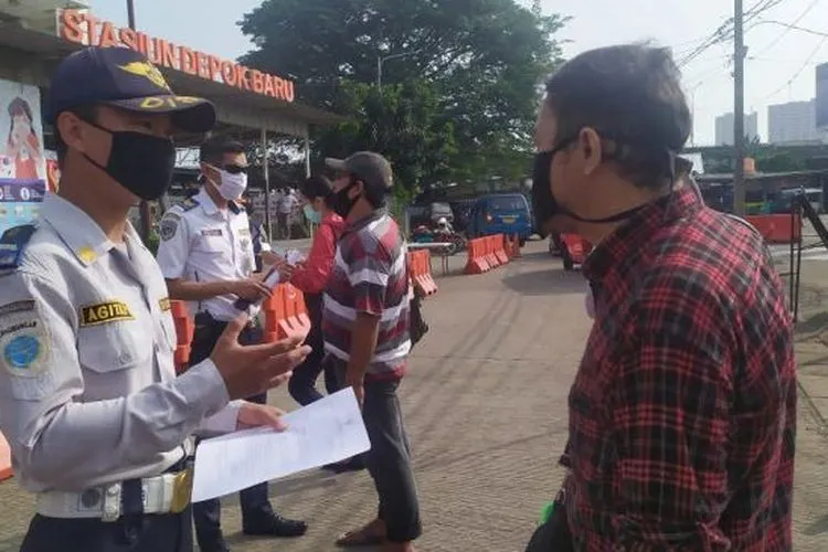 Petugas Dishub Kota Depok menanyakan kelengkapan surat untuk calon penumpang KRL di Stasiun Depok Baru, Rabu (13/5/2020). (Suara.com/Supriyadi)
