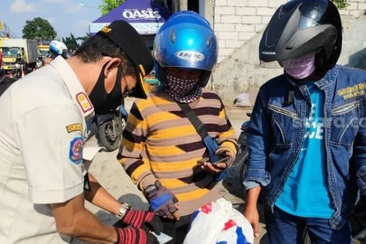 Petugas Dishub saat memeriksa SIKM terhadap pengendara motor di kawasan Pasar Rebo, Jaktim. (Suara.com/Bagaskara).