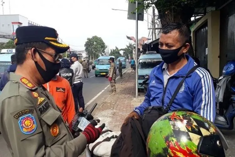 Petugas saat memeriksa SIKM dan KTP pengendara di check point PSBB Pasar Rebo, Jaktim. (Suara.com/Bagaskara).