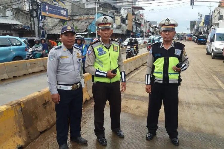 Petugas polisi lalu lintas dan Dinas Perhubungan berfoto di ruas Jalan Jatinegara Barat yang sebelumnya terendam banjir hingga tak bisa dilalui kendaraan. (Twitter @TMCPoldaMetro)