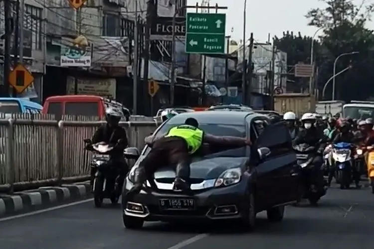 Anggota Unit Laka Lantas Polsek Pasar Minggu, Bripka Eka Setiawan menempel di atas bmobil dengan kondisi melaju/Dok Pribadi