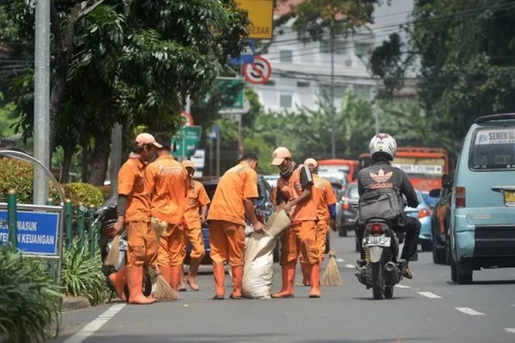 Petugas PPSU membersihkan sampah di jalan (Tirto.id)