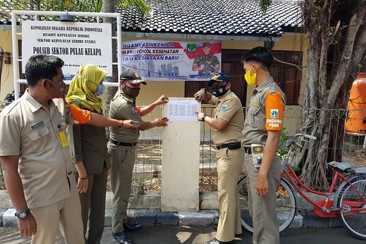 Para pejabat Pemkab Kepulauan Seribu sedang menempelkan daftar nama-nama pelanggar protokol kesehatan di depan kantor Polsub Kepulauan Seribu. sumber: pulauseribu.jakarta.go.id