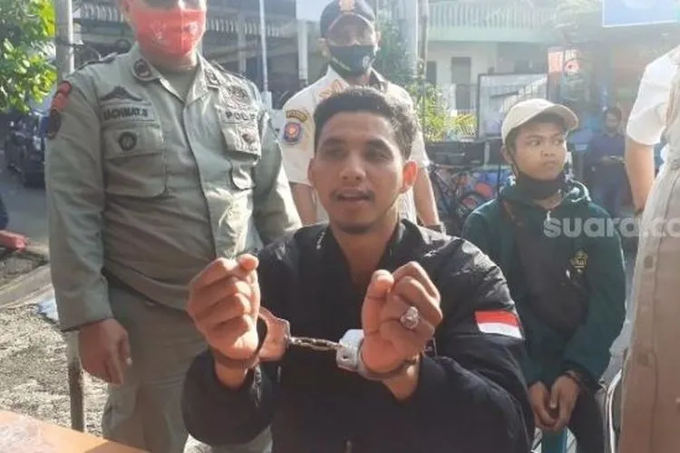 Seorang pengendara roda dua bernama Andi Albar saat memperlihatkan tangannya di borgol karena tidak mengguna masker di Jalan Raya Puncak Bogor Jawa Barat. (Suara.com/Andi Ahmad Sulaendi).