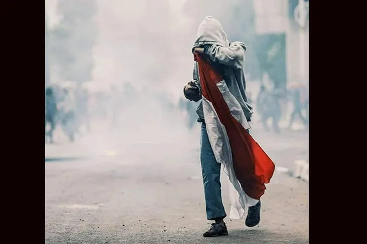 Foto viral pelajar SMA memegang bendera merah putih di tengah kepungan kabut asap gas airmata yang ditembakkan aparat/Media Sosial