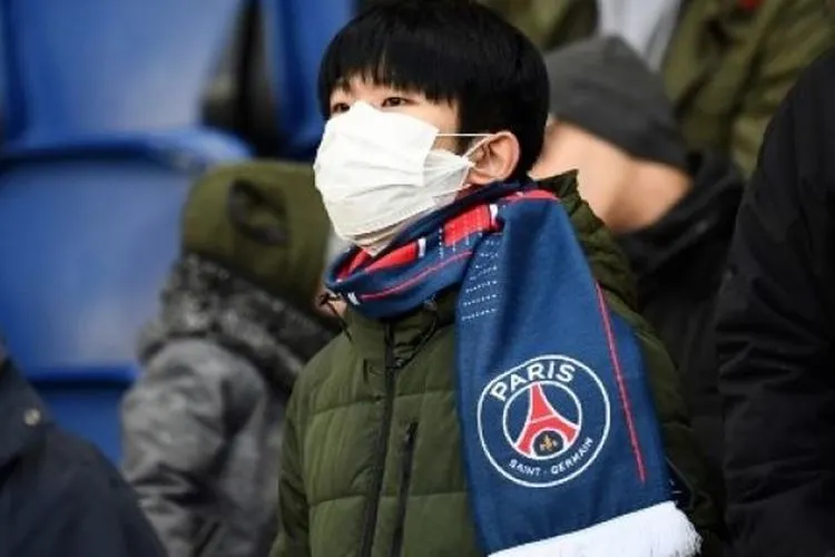 Suporter Paris Saint-Germain (PSG) memakai masker meyusul merebaknya virus corona saat menyaksikan laga melawan Dijon pada laga lanjutan Ligue 1 di Parc des Princes stadium, Paris. FRANCK FIFE / AFP
