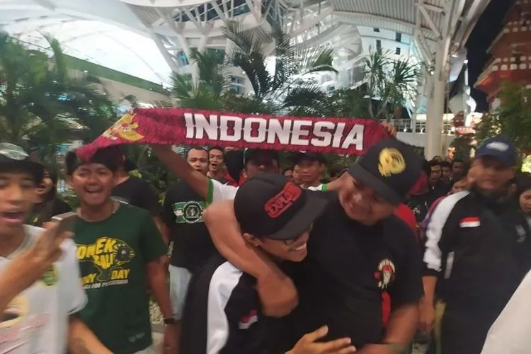 Suporter Indonesia, Andreas Setiawan (dirangkul), yang sempat ditahan Polisi Malaysia terkait komentar di media sosial yang dicurigai sebagai teror, tiba di Bandara Internasional I Gusti Ngurah Rai, Bali, Jumat malam (29/11/2019). (Kumparan.com)
