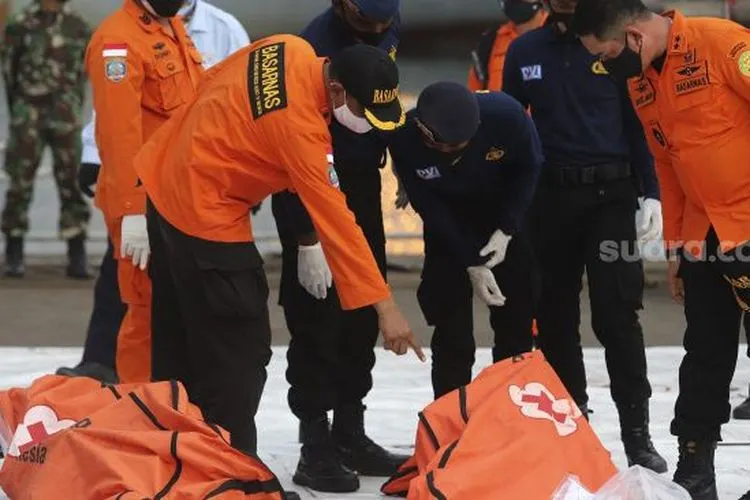 Petugas gabungan memeriksa kantung jenazah berisi bagian tubuh korban pesawat Sriwijaya Air SJ 182 rute Jakarta - Pontianak yang hilang kontak di perairan Kepulauan Seribu, di Dermaga JICT, Tanjung Priok, Jakarta, Senin (11/1/2021). [Suara.com/Angga Budhiyanto]