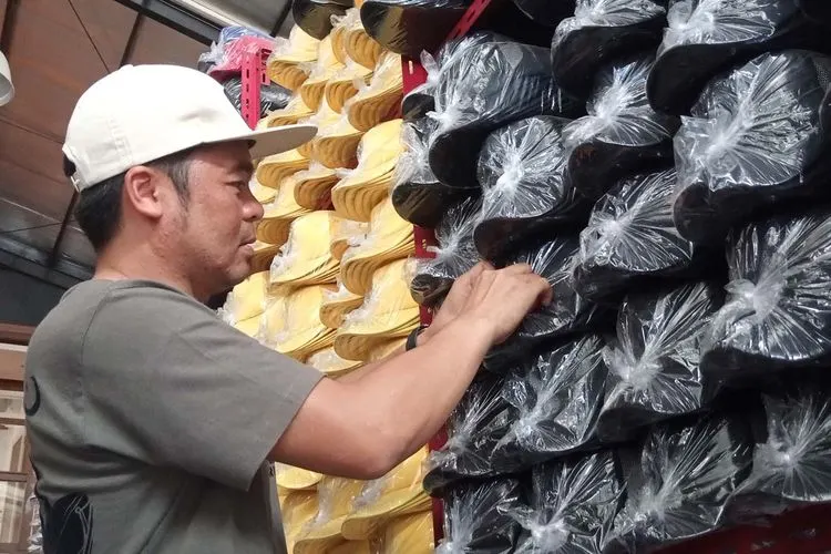 Asep Andyan, salah satu pelaku usaha UMKM Topi Desa Rahayu, menata topi hasil produksinya. (Ayobandung/Mildan Abdalloh)