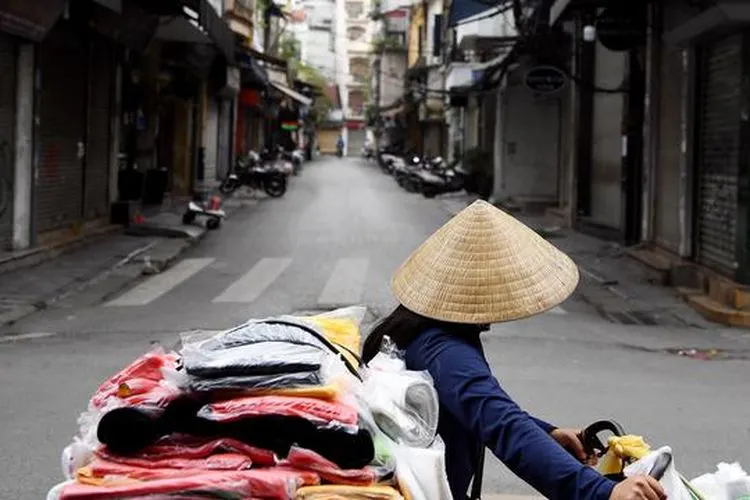Seorang penjual berjalan melewati jalan sepi di tengah kekhawatiran tentang penyebaran Virus Corona COVID-19 di Hanoi Vietnam pada 26 Maret 2020. (Liputan6/Nhac Nguyen-AFP)