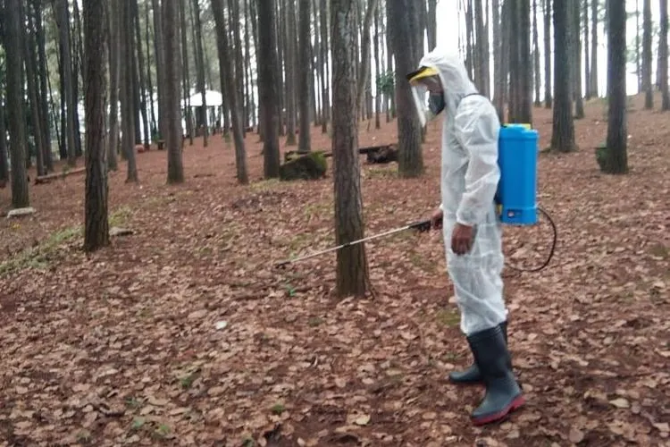 Seorang petugas saat menyemprotkan disinfekstan di salah satu tempat wisata, persiapan dibuka kembali. (Ayobandung/M Ikhsan)