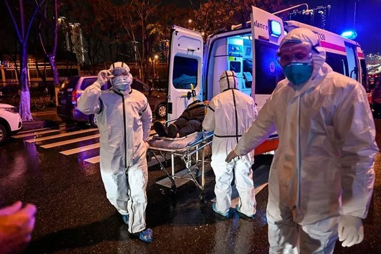 Para petugas medis mengenakan pakaian pelindung saat membawa seorang pasien ke Rumah Sakit Palang Merah Wuhan di Hubei, China pada 25 Januari 2020. (AFP/Via Getty Images/Hector Retamal)