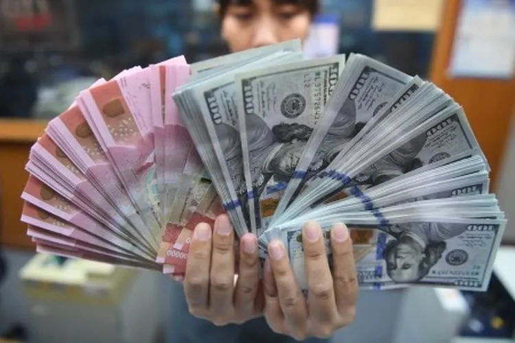 Pekerja menunjukkan uang Rupiah dan Dollar Amerika Serikat di sebuah tempat penukaran uang di Jakarta, Kamis (28/3/2019). Pada penutupan perdagangan, Rupiah menjadi salah satu mata uang dengan kinerja terburuk di kawasan Asia setelah ditutup melemah 0,25 persen ke level 14.243. ANTARA FOTO/Akbar Nugroho Gumay/wsj.