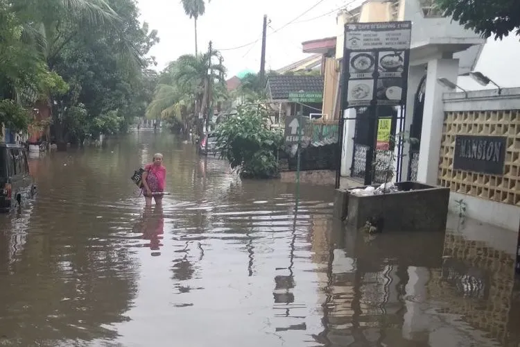 Seorang warga melintasi banjir yang melanda kawasan Rawalumbu, Bekasi Timur, Rabu (24/4/2019) petang, sementara sebuah kendaraan tampak terendam banjir. (Rangga Pandu/Antara Foto)