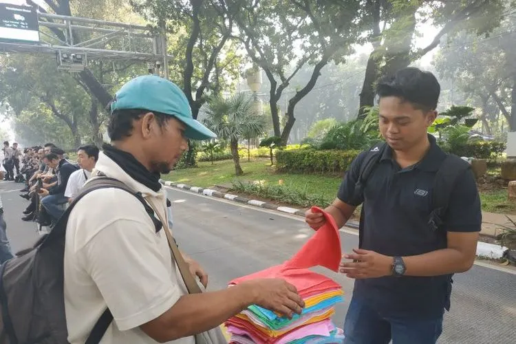 Transaksi jual beli pedagang handuk keliling di kawasan Tugu Patung Kuda Monas, Jakarta, Rabu, (26/06/2019). (Boyke Ledy Watra)
