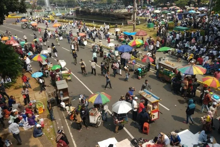 Sejumlah pedagang menggelar dagangannya di Jalan Medan Merdeka Barat ketika berjalannya aksi unjuk rasa sidang putusan Mahkamah Konstitusi, Kamis (27/6/2019). (antara/Asep Firmansyah)