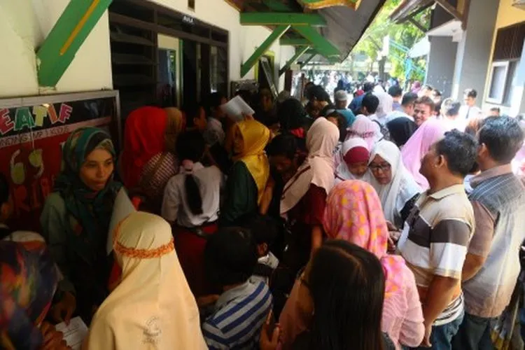 Sejumlah siswa dan orang tua murid antre untuk mengikuti seleksi Penerimaan Peserta Didik Baru (PPDB) di SMP 1 Kudus, Jawa Tengah, Rabu (19/6/2019). Sistem PPDB dengan mekanisme berdasarkan sistem jalur zonasi tersebut menyebabkan antrean panjang dan siswa datang lebih pagi di tiap sekolah negeri di wilayah itu. ANTARA FOTO/Yusuf Nugroho/pd.