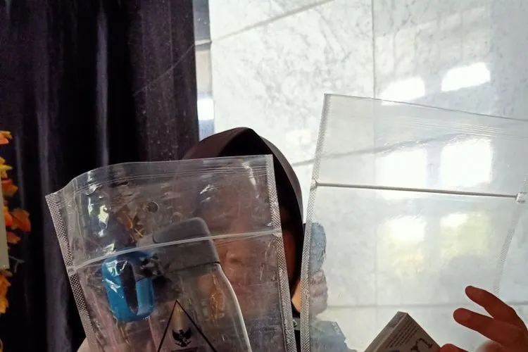 Polwan petugas pengaman ruang sidang Mahkamah Konstitusi (MK) memperlihatkan barang sitaan berupa rokok dan korek api milik sejumlah tamu di ruang sidang MK, di Jakarta, Kamis (27/6/2019). (ANTARA/Andi Firdaus)