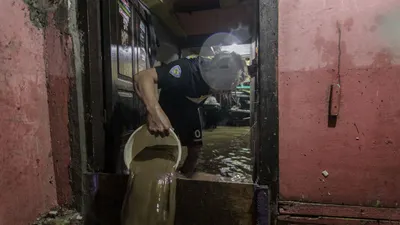 Warga merapikan barang-barang di dalam rumahnya di kawasan Gang Apandi, Kelurahan Braga, Kecamatan Sumur Bandung, Kota Bandung, Kamis 11 Januari 2023. Banjir yang menggenangi pemukiman warga tersebut terjadi disebabkan oleh  jebolnya tanggul sungai Cikapundung. (Ayobandung.com/Magang Foto/Ilham Ahmad Nazar)