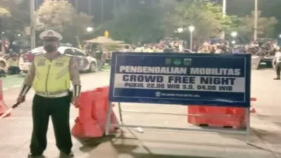 Ilustrasi. Seorang anggota polisi tengah berjaga di depan papan petunjuk penerapan crowd free night di Jakarta.