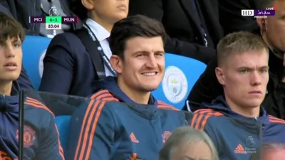 Manchester United kalah, Harry Maguire yang tengah berada di bangku cadangan dengan muka tersenyum disorot.