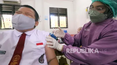 Seorang petugas kesehatan memberikan dosis vaksin COVID-19 kepada seorang siswa sekolah dasar selama perjalanan vaksinasi untuk anak-anak antara usia enam hingga 11 tahun