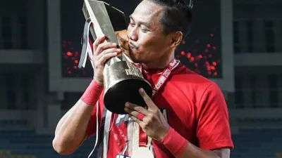 Tony Sucipto mencium sebuah tropi juara yang diraih Persija Jakarta.