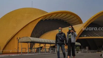 Sepasang kekasih melintas di depan Teater Keong Mas di Taman Mini Indonesia Indah, Jakarta Timur, Minggu (13/9). [Suara.com/Alfian Winanto]