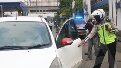 Polisi melakukan pengecekan terhadap pengendara yang keluar tol seiring pemberlakuan Pembatasan Sosial Berskala Besar (PSBB) di Kota Bekasi, Rabu (15/4/2020). (Ayobekasi.net/Firda Puri Agustine)