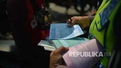 Anggota dari Polres Metro Jakarta Selatan memberikan surat tilang kepada pengendara motor saat menggelar Operasi Patuh Jaya.  Foto: Republika/Raisan Al Farisi