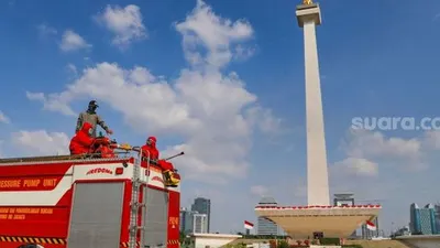 Petugas Pemadam Kebakaran menyemprotkan cairan disinfektan di Kawasan Monumen Nasional (Monas), Jakarta Pusat, Rabu (17/6/2020). (Suara.com/Alfian Winanto)