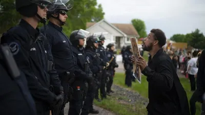Seorang demonstran berhadapan dengan polisi di rumah petugas kepolisian Minneapolis Derek Chauvin yang dipecat pada Rabu (27/5). Walikota Minneapolis menelepon hari Rabu untuk tuduhan kriminal terhadap petugas polisi kulit putih yang terlihat di video berlutut di leher Floyd George, seorang pria kulit hitam terborgol yang mengeluh bahwa ia tidak bisa bernapas dan meninggal dalam tahanan polisi. Jeff Wheeler / Star Tribune via AP  Foto: Jeff Wheeler / Star Tribune via AP
