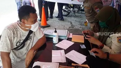 Pelanggar PSBB yang dikenakan sanksi sosial oleh petugas di check point Pasar Rebo, Jaktim. (Suara.com/Bagaskara).