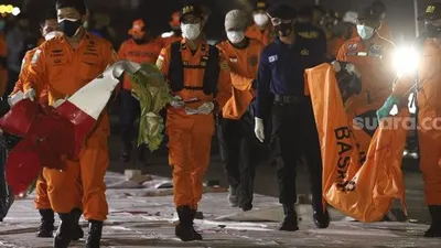 Petugas Basarnas membawa kantong jenazah berisi bagian tubuh korban dan serpihan pesawat Sriwijaya Air SJ 182 rute Jakarta - Pontianak yang hilang kontak di perairan Kepulauan Seribu, di Dermaga JICT, Tanjung Priok, Jakarta, Senin (11/1/2021). [Suara.com/Angga Budhiyanto]