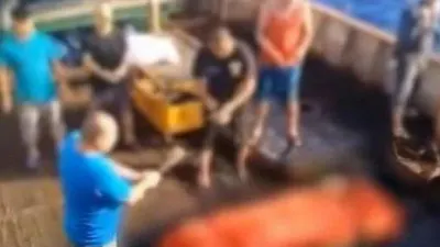Screenshot dari rekaman video yang dipublikasikan media Korea Selatan MBC memperlihatkan, seorang awak kapal tengah menggoyang sesuatu seperti dupa di depan kotak yang sudah dibungkus kain berwarna oranye. Disebutkan bahwa kotak tersebut merupakan jenazah ABK asal Indonesia yang dibuang ke tengah laut oleh kapal asal China. (MBC/Screengrab from YouTube)