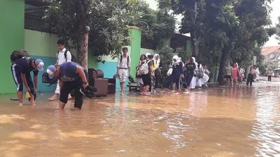 Murid SMAN 8 terpaksa pulang dengan menenteng sepatu akibat banjir yang merendam kawasan gedung sekolah mereka pada April 2019). (Kompas.com/Ardito Ramadhan)
