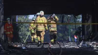Petugas Damkar DKI berjalan keluar usai melakukan proses pendinginan di Gedung Utama Kejaksaan Agung RI di Jalan Sultan Hasanuddin, Jakarta Selatan, Minggu (23/8). [Suara.com/Alfian Winanto]