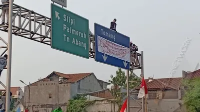 Sejumlah mahasiswa memanjat papan penunjuk jalan di tengah tol dalam kota seberang gedung DPR, Senayan, Jakarta Pusat dan memasang spanduk protes/Ayojakarta.com