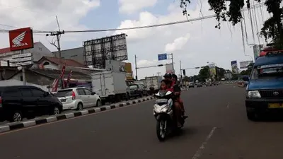 Pengendara motor di PSBB Depok berboncengan tiga, tanpa helm, dan tidak menggunakan masker. (Suara.com/Novian)
