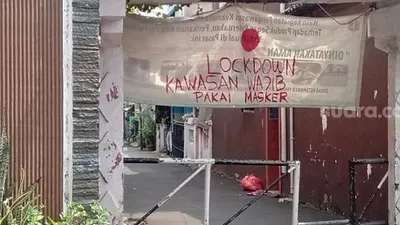 Penampakan tulisan lockdown kawasan wajib pakai masker di RW Zona Merah di Kelurahan Malaka Jaya, Duren Sawit. (Suara.com/Arga).