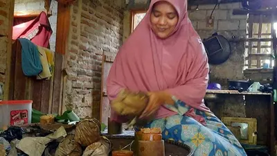 Istri Ujang Aeful saat membungkus gula aren menggunakan daun pisang kering sebelum dijual. (Ayoprwakarta/Dede Nurhasanudin)