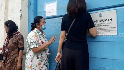 Yemi, dan Kerabat Keraton lain saat mencoba mengetok pintu dari sasonoputro untuk masuk memberikan makan serta minum untuk kerabat yang terkurung di dalam, Jumat (12/2/2021). (suara.com)