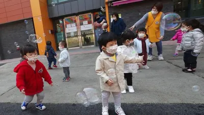 Anak-anak bermasker tengah bermain balon di Kuil Chogyesa di Korea Selatan, Jumat (24/4/2020). Pemerintah Korea Selatan merencanakan akan melakukan pengumuman untuk memulai mendatangkan kembali siswa ke sekolah paling lambat awal Mei. (AP Photo/Ahn Young-joon)