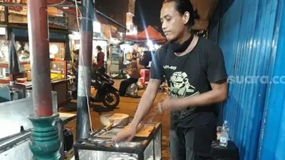 Koki sajian kuliner ekstrem Ian Suhendi (32) sedang memasak di tenda miliknya 'Tenda Dua Kobra' yang menyajikan makanan berbahan dasar kobra, biawak, dan kalong/ Suara.com